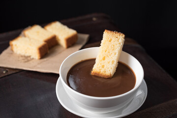 Chocolate caliente en taza blanca con bizcocho en una vieja maleta marrón. Desayuno Español