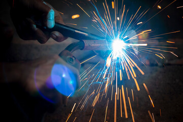 Welding of steel, sparking, not wearing gloves, light colored like fireworks.