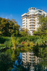 Beautiful garden pond with subtropical exotic plants nearby Winter Theater in center Sochi. Modern building reflected with plants in water surface. Sochi, Russia - November 25, 2020