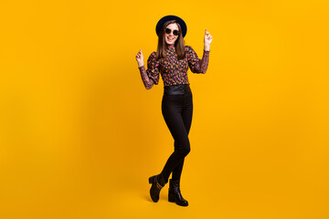 Obraz premium Full length body size photo of smiling female student dancing on floor clicking fingers in headwear isolated vibrant yellow color background