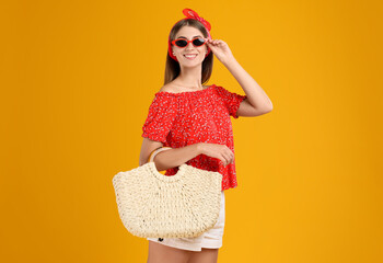 Beautiful young woman with stylish straw bag on yellow background