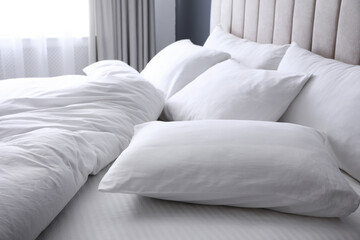 Fototapeta na wymiar Comfortable bed with soft white pillows, closeup