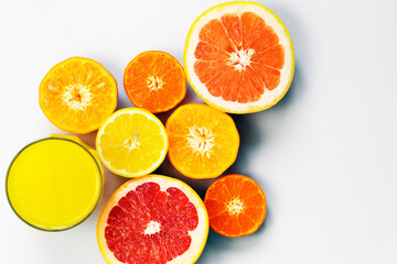 Sliced citrus on a white background with a glass of fresh juice. Grapefruit, lemon, tangerine