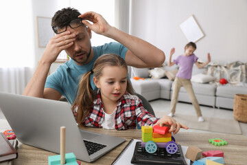 Children disturbing stressed man in living room. Working from home during quarantine