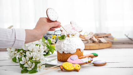 Women's hands decorate the Easter cake with festive gingerbread on sticks.