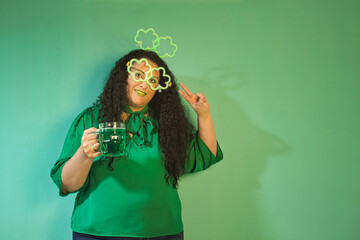 Woman celebrating St. Patrick´s Day with luminous shamrock glasses and headband, with green beer mug.