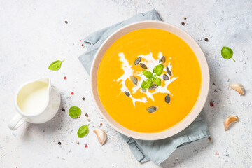 Pumpkin soup with cream. Top view image at white table.