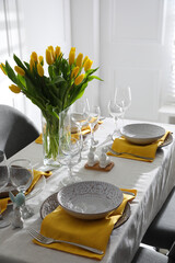 Beautiful Easter table setting with yellow tulips indoors