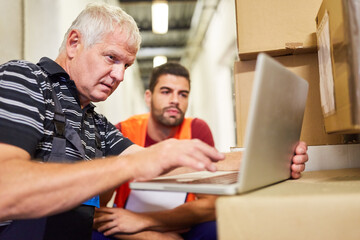 Two warehouse workers at the laptop computer