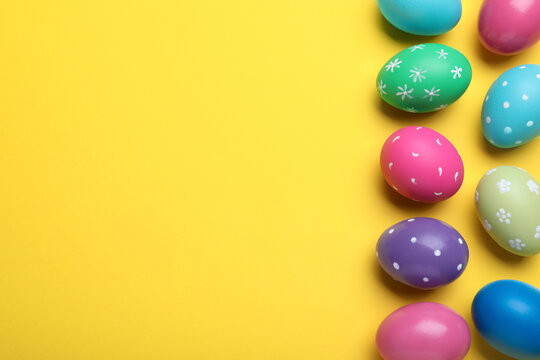 Bright painted eggs on yellow background, flat lay with space for text. Happy Easter