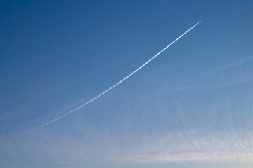 Sky with an airplane taking off and a contrail