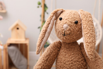 Cute toy rabbit in room, closeup. Space for text
