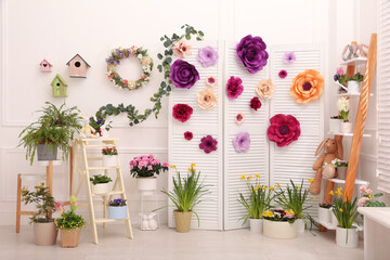 Fototapeta na wymiar Easter photo zone with plants and paper flowers indoors