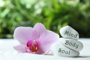 Stones with words Mind, Body, Soul and orchid on sand. Zen lifestyle