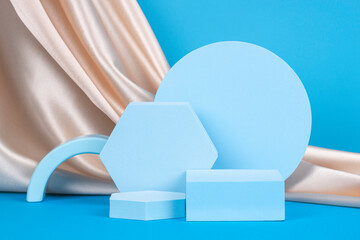 Geometric podium on light blue background with draped champagne color silk cloth. Empty showcase...