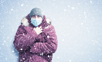 Frozen man in red winter clothes on his face wearing a respirator mask to protect against the virus covid, snow around