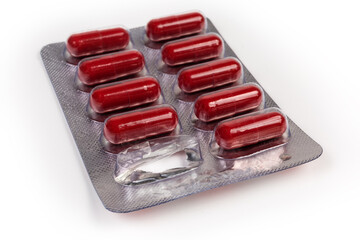 Dark red capsules in started blister packing on light surface