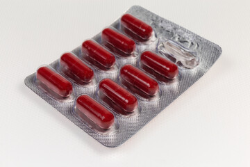 Red capsules in started blister packing on light colored surface
