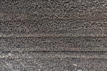 Winter frost on a dark surface close-up. The concept of winter. Abstract background