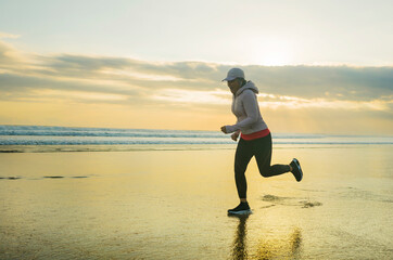 fit and attractive mature woman with grey hair doing beach workout on her 50s running on the beach happy and free in senior fitness selfcare and wellness concept