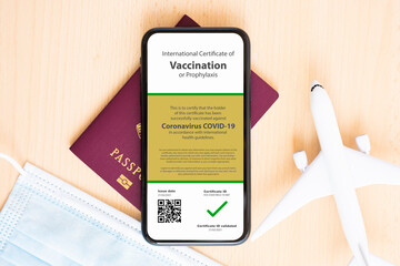 A face mask, model aircraft, passport and a smartphone with a Certificate of Vaccination against...