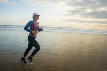 fit and attractive mature woman with grey hair doing beach workout on her 50s running on the beach...