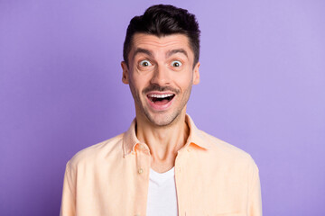 Portrait of impressed funny brunet hair guy wear peach shirt isolated on lilac color background