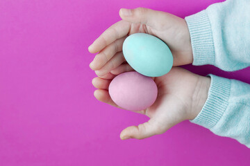 Easter painted eggs in the hands of a child on a bright pink background