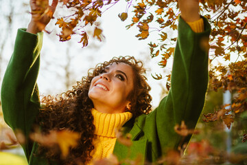 beauty with a smile white raised up her hands and plucked autumn yellow leaves from the tree. High...