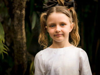 Close up portrait of pretty little girl. Blue eyes and blond hair. Caucasian girl with two...