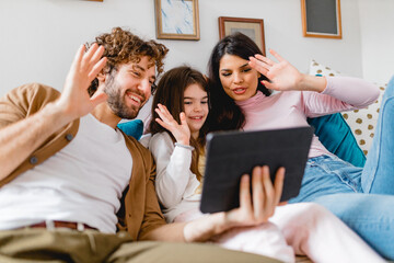 Family waving hands and using tablet for video call
