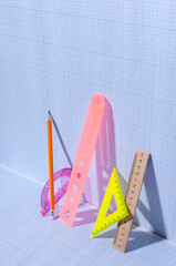 Vertical image.Wooden and colorful plastic rulers on the blank blue graph paper