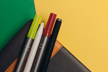 notepad with markers and pens on yellow green background and office supplies codespace
