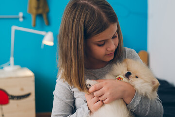 girl playing with her puppy at home