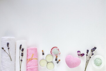 Spa cosmetics and towels, dry lavender, aroma oils and sea salt on a white background