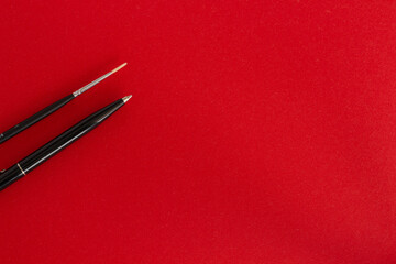 Black pen, pencil and brush on red background