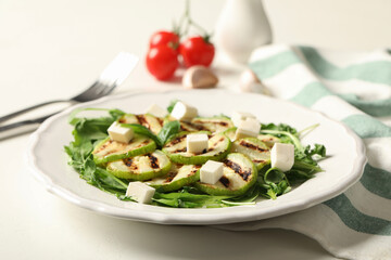 Grilled zucchini slices and feta cheese served on white table, closeup