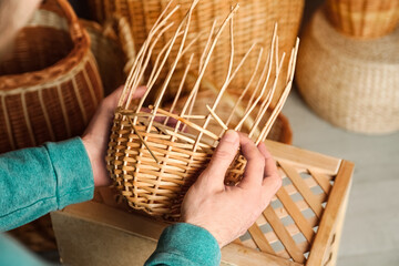 Fototapeta Man weaving wicker basket indoors, closeup view obraz