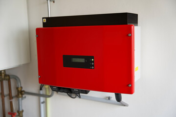 red solar power inverter mounted on a white wall. Sustainable energy production. Green power....