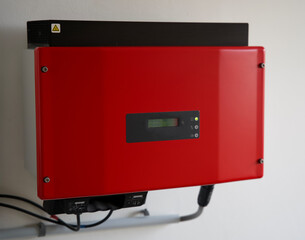 red solar power inverter mounted on a white wall. Omvormer for solar energy. Transforming to 230V...