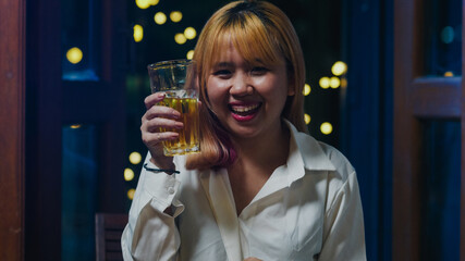 Young Asia lady drinking beer having fun happy night party New Year event online celebration via video call by phone at home at night. Social distance, quarantine for coronavirus. Point of view or POV