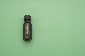 Essential oils in a bottle placed on a green background. Space for text. Top view photo