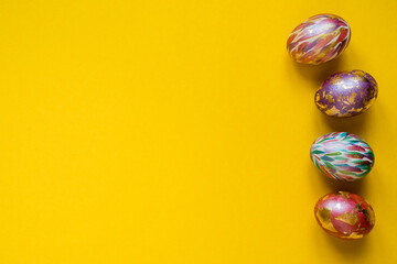 Colorful Easter eggs on yellow background, copy space.