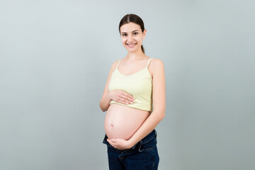 pregnant belly at colorful background with copy space. Expecting mother in opened jeans. Motherhood concept