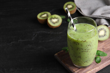 Delicious kiwi smoothie and fresh ingredients on black table, space for text