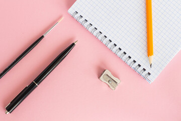 Student concept. Pen, notebook, pencil on a pink background