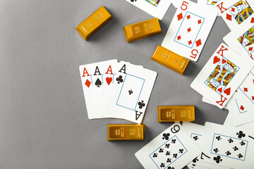 Playing cards and gold bars on gray background