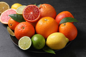 Different citrus fruits on black table, closeup