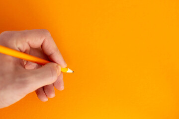 Hand holds a pencil on a colorful background