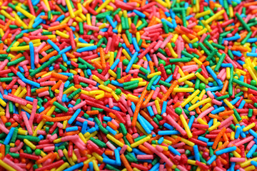 Bright colorful sprinkles as background, closeup. Confectionery decor